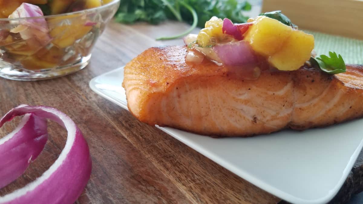 A plate with salmon topped with mango salsa